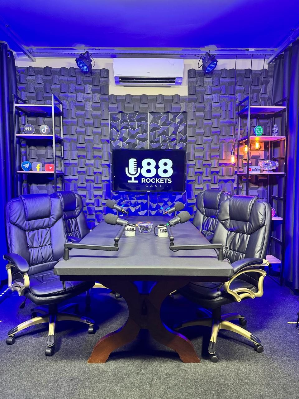 Cenário do estúdio de podcast em Campinas com quatro cadeiras e microfones sobre a mesa