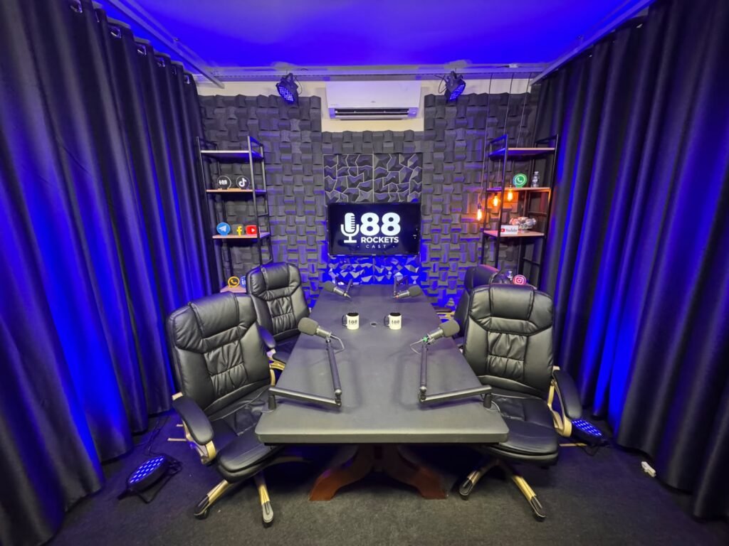 Estúdio de podcast em Campinas com mesa para quatro pessoas, microfones profissionais e painel de LED
